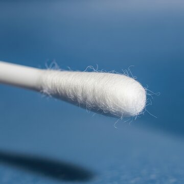 Detailed macro shot of a sterile white cotton swab with fluffy cotton tip on a textured blue surface