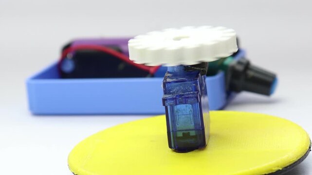 Small servo with 3D printed gear attached to its shaft is controlled by a speed controller in the background