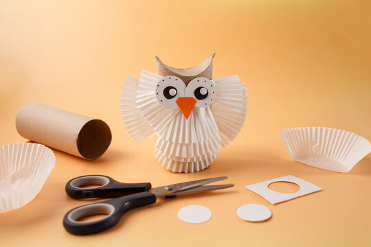 Handmade toilet paper roll owl toy and craft supply for daycare center, kids birthday party organizer, parenting blog, craft store, pink background, selective focus