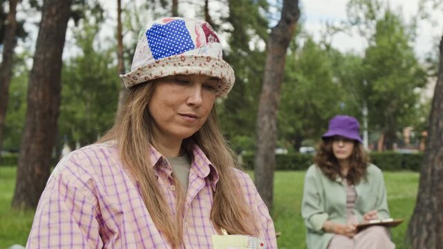 Caucasian woman measuring proportions with pencil and sketching in park during art class. Video is perfect for promoting creative workshops and adult education programs