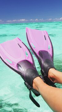 Snorkel fun. Legs snorkeling fins over water at travel luxury vacation. Snorkeler relaxing on overwater villa deck at resort holiday. Raw unedited vertical video of real woman model.