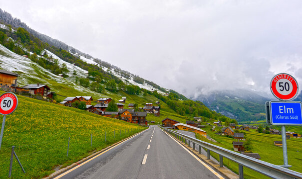 Malerische Ortseinfahrt im Alpendorf Elm im Kanton Glarus bei bew&ouml;lktem Wetter, Schweiz
