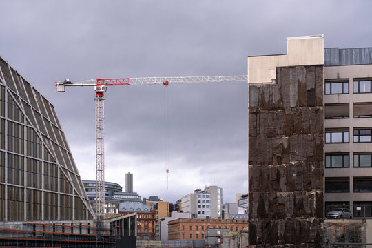 Above an Oslo, Norway, cityscape, clouds hang while construction and a crane extend office blocks and urban architecture across the skyline.