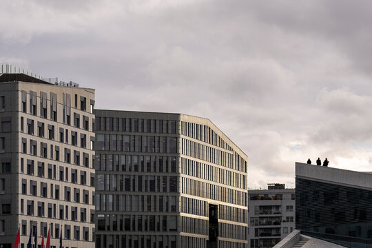 Across Oslo, Norway, clouds settle over a modern office skyline, where urban architecture and a measured facade define the restrained cityscape.