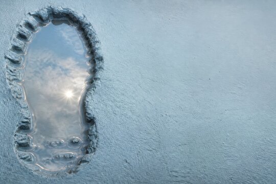 Winter Footprint in Snow with Water Reflection and Minimal Blue Texture