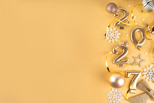 Merry Christmas Happy New Year 2027 background, New year 2027 celebration greeting card, Numbers candles 2027 with golden party decoration on gold background. Christmas, Noel New Year holidays banner