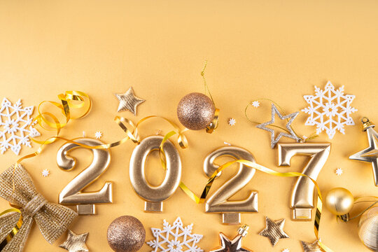 Merry Christmas Happy New Year 2027 background, New year 2027 celebration greeting card, Numbers candles 2027 with golden party decoration on gold background. Christmas, Noel New Year holidays banner