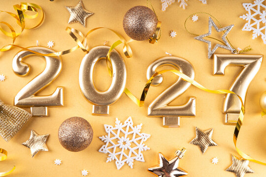 Merry Christmas Happy New Year 2027 background, New year 2027 celebration greeting card, Numbers candles 2027 with golden party decoration on gold background. Christmas, Noel New Year holidays banner