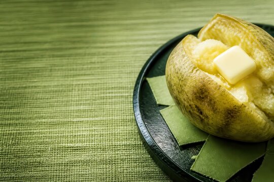 Warm baked potato with butter on a green textured setting