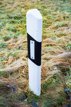 White and black delineator post standing in green grass
