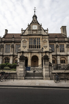 View of the historic Examination Schools building with its ornate stone facade, clock tower, and iron gates in Oxford, England, United Kingdom.