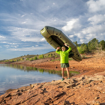 senior male paddler is launching an inflatable packraft on a shore of Horsetooth Reservoir in Colorado