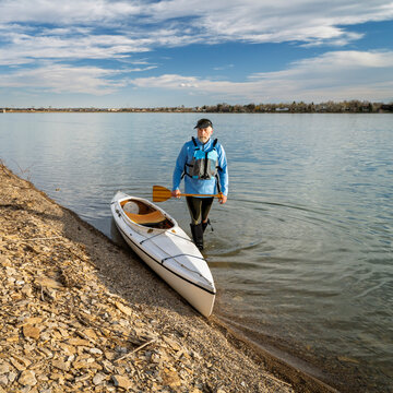 senior male paddler with expedition decked canoe on a lake shore in early spring, Boedecker Reservoir in northern Colorado