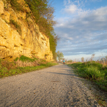 distant male cyclist riding a folding bike on Steamboat Trace, bike trail converted from an abandoned railroad, near Peru, Nebraska, springtime morning scenery
