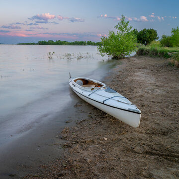 expedition decked canoe on a lake shore at dusk after paddling, Boyd Lake in northern Colorado