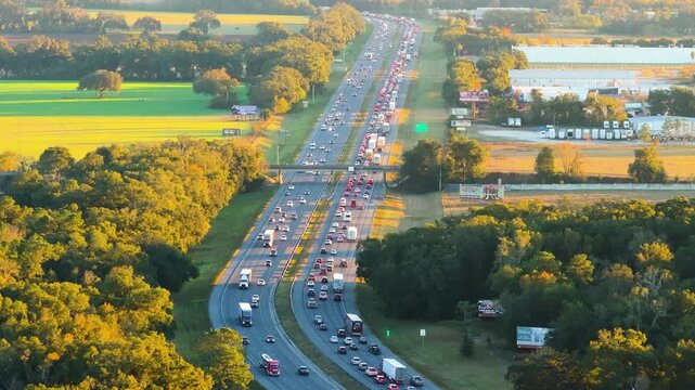 Panoramic aerial view of American freeway with cars and trucks navigating wide lanes. Large transportation hub connecting interstate highways and urban roads.
