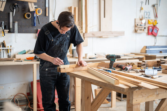 Restoration workshop settings and woodworking, focused man restorer rebuilding window frame at worktable, craftsperson measuring planks with ruler, creative process of remaking and renewing aged items