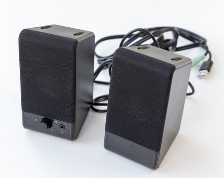 Two black computer speakers with cables on a clean white background