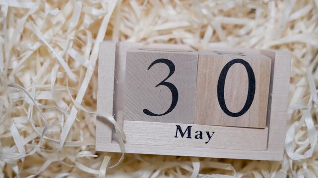 Wooden calendar blocks showing date May 30 on natural wood shavings background