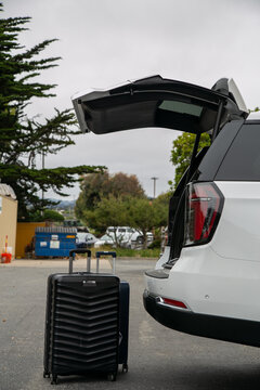 Travel-ready scene featuring packed suitcases positioned beside a premium SUV with its boot open, ready for loading. The image represents holiday preparation, road travel, family vacation