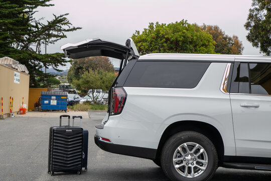 Travel-ready scene featuring packed suitcases positioned beside a premium SUV with its boot open, ready for loading. The image represents holiday preparation, road travel, family vacation
