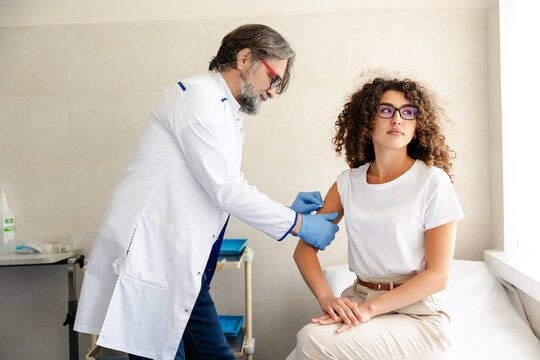 Doctor giving vaccination injection to female patient in clinic