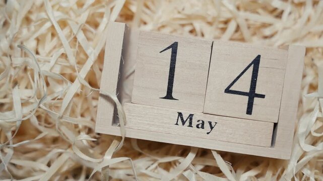 Wooden calendar blocks showing date May 14 on natural wood shavings background