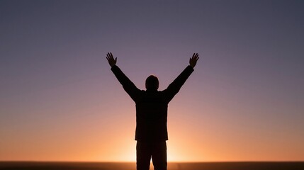 Fototapeta premium Silhouette of a person with arms raised in triumph against a vibrant sunset sky background