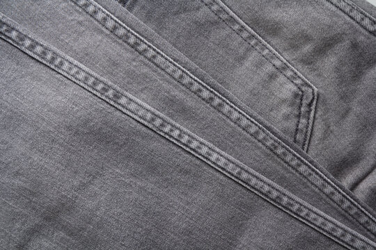 Gray denim jeans close up texture and seam detail.