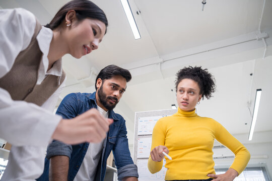 Confident corporate team collaborating on a project, with a male manager pointing at documents while discussing ideas with colleagues.