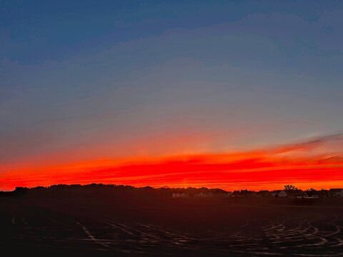 Dramatic bright orange and red sunset sky over dark horizon