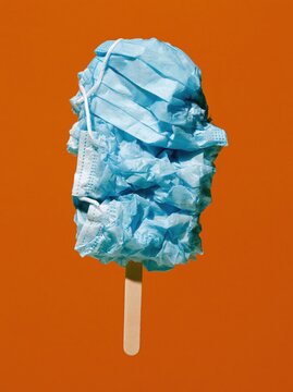 Blue Surgical Mask Ice Pop with Crumpled Mask Texture on Warm Orange Background