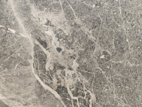 Close up view of dark grey breccia marble texture with prominent white veins and stone fragments
