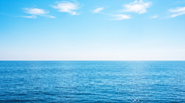 Panoramic view of calm blue ocean horizon with clear sky and light clouds