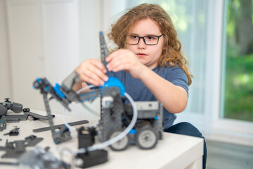 Fototapeta premium Science project supports smart childhood education. Science learning develops brain and motor skills. Focused child explores science through robotics. Home workshop shows science innovation concept.