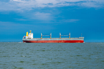 Fototapeta premium Cargo ship sails through coastal waters. Cargo ship carries international sea freight. Large cargo ship serves global logistics. Commercial cargo ship drives worldwide trade.