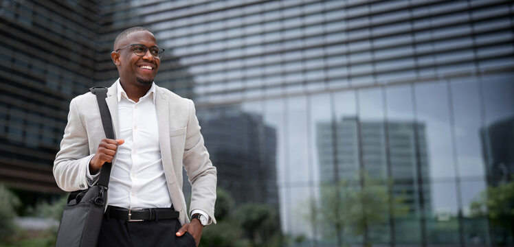 CEO, african american businessman, posing for confident portrait, hand in pocket, outdoor near office building. Black business man smiling, staying productive throughout day. Copy space. Web banner.