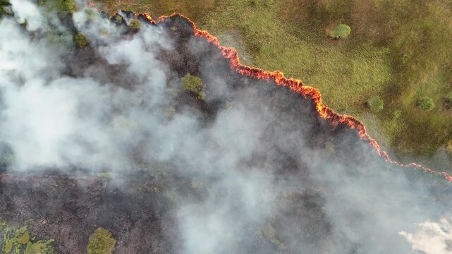 Aerial view of a wildfire burning through dry grassland with thick smoke rising in Banjarbaru, South Kalimantan, Indonesia.