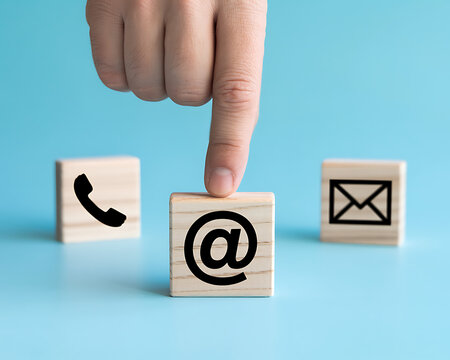 Finger touching email icon on wood block