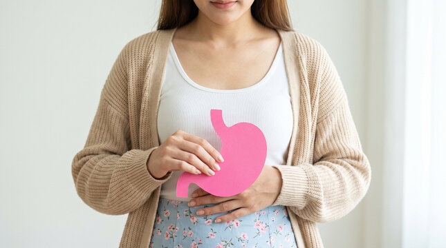 Woman holding pink stomach paper cutout against abdomen, representing digestive health and gastrointestinal care