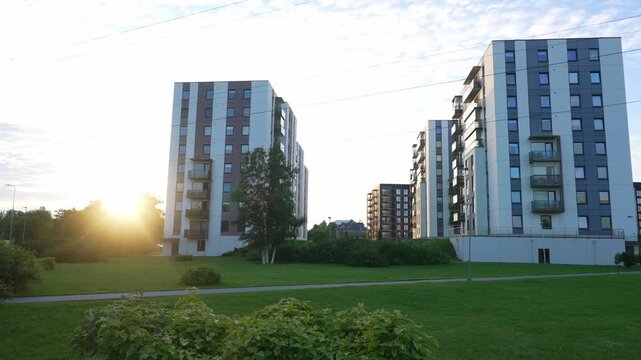 Modern residential apartment buildings in a green park area at sunset.