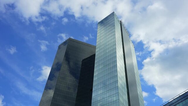 Modern glass skyscrapers and corporate office towers reflecting blue sky.