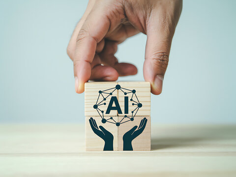 Hand holding wooden cube with ai symbol