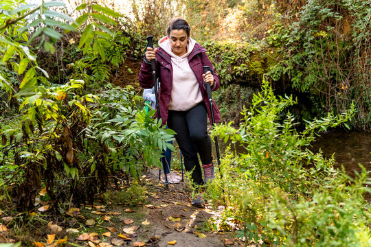 Woman enjoying nordic walking during autumn hike, embracing outdoor fitness and nature