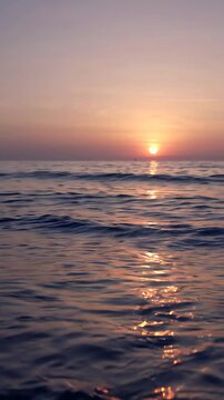 Beautiful sunset over the calm ocean horizon with golden light reflecting on the water surface.