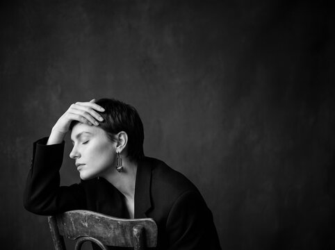 Melancholy Reflection: A pensive woman with a short hairstyle rests her head on her hand, her eyes closed in a moment of quiet contemplation or sadness.