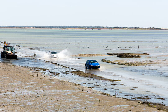 V&eacute;hicules roulant sur une route presque recouverte par la mer, engag&eacute;s sur le passage &agrave; mar&eacute;e descendante. Le Gois, &icirc;le de Noirmoutier.