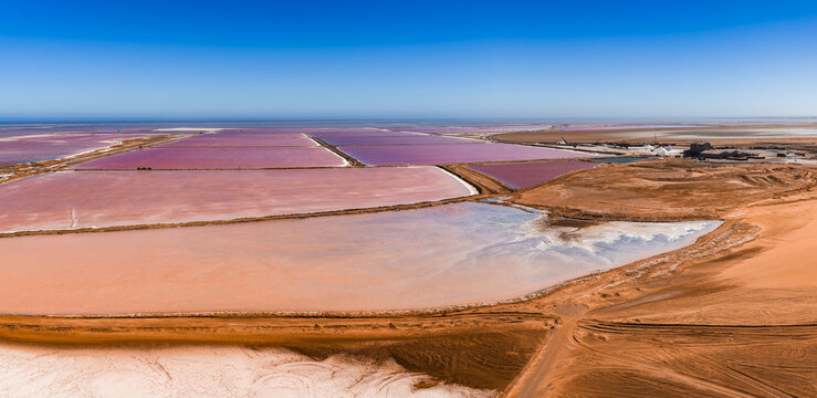 Aerial view of the extensive salt flats, pink evaporation ponds, and desert landscape at Walvis Bay in Namibia, showing industrial salt production.