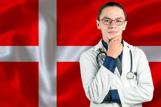 Male doctor on Denmark flag. Smiling doctor with Denmark flag behind him. Denmark health and care concept