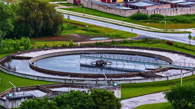 Aerial view of a circular wastewater treatment plant with industrial infrastructure and surrounding green fields in Latvia.